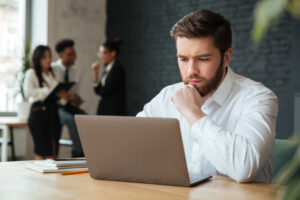 Egy fiatal férfi egy íróasztalnál ülve dolgozik a laptopján, digitális marketinggel foglalkozik, és a Konverzió Pro Google Ads kampányainak menedzselését végzi.
